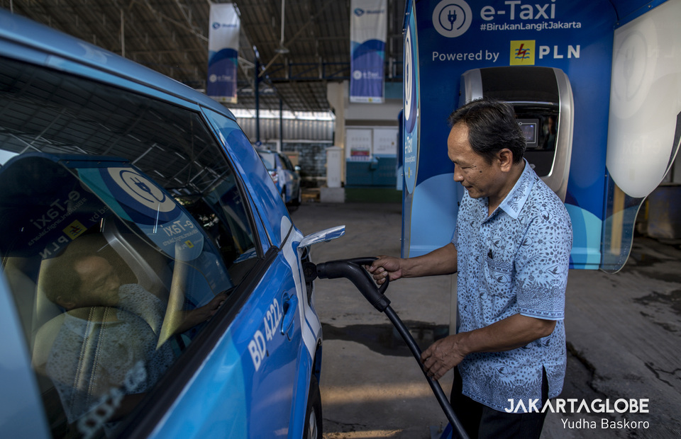 A driver charges a BYD e6 electric taxi at the Blue Bird Group's headquarters in Mampang, South Jakarta, on Friday. (JG Photo/Yudha Baskoro)