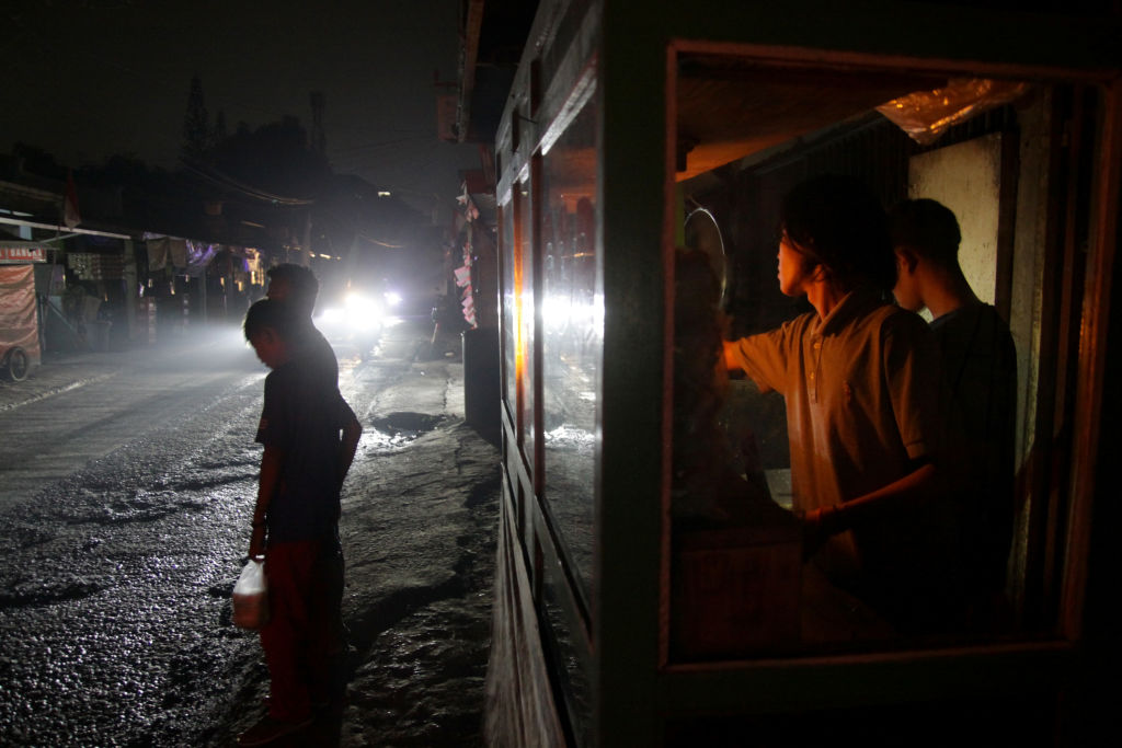 Food vendors serve customers by lantern light on 5 August, the second day of an electricity blackout in Wanasari Village, West Java